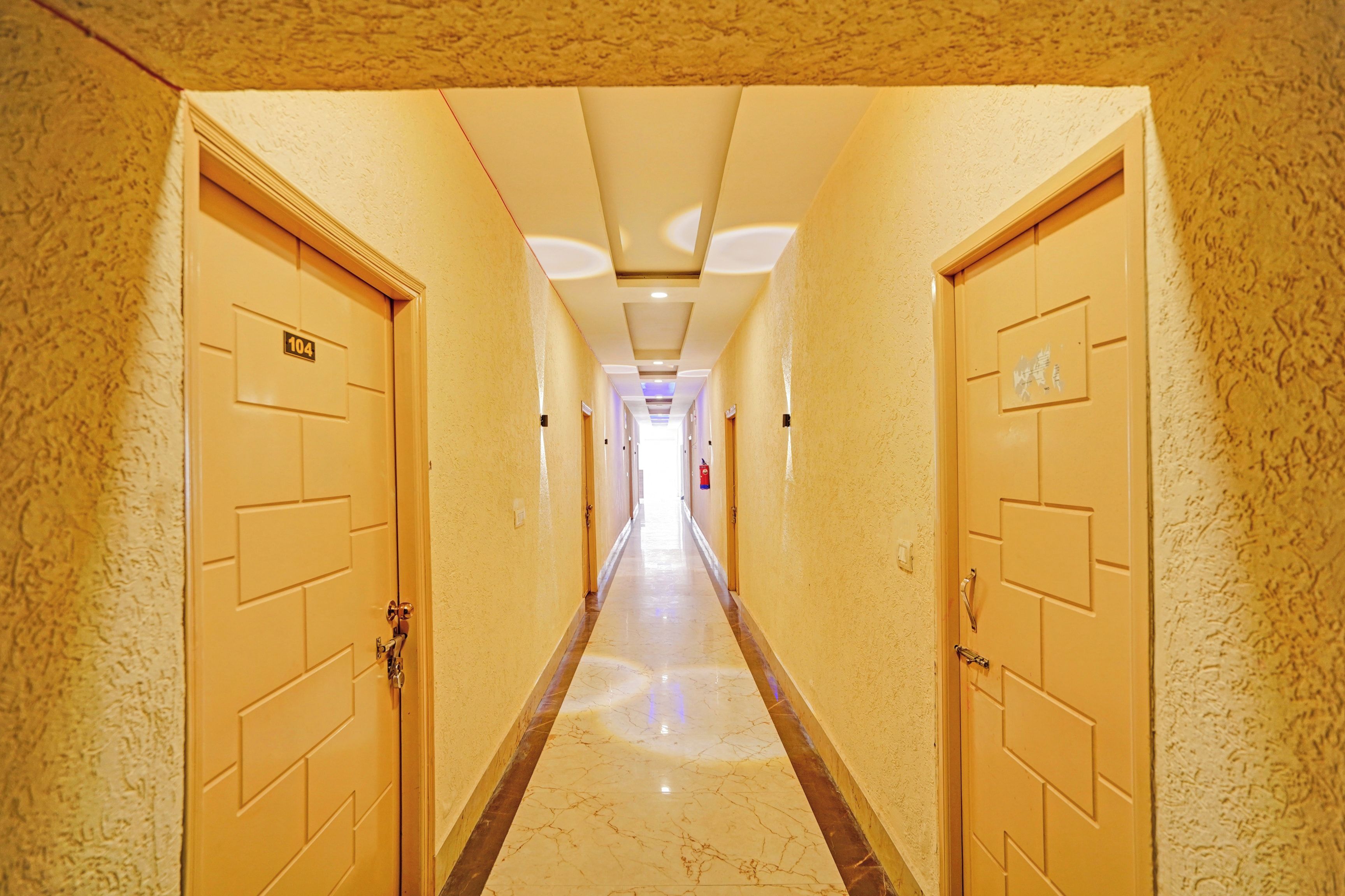 A hotel corridor with doors on both sides, a marble floor, and a ceiling with recessed lighting.