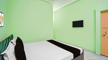A room with a bed, a door, a wall-mounted TV, and a framed picture.