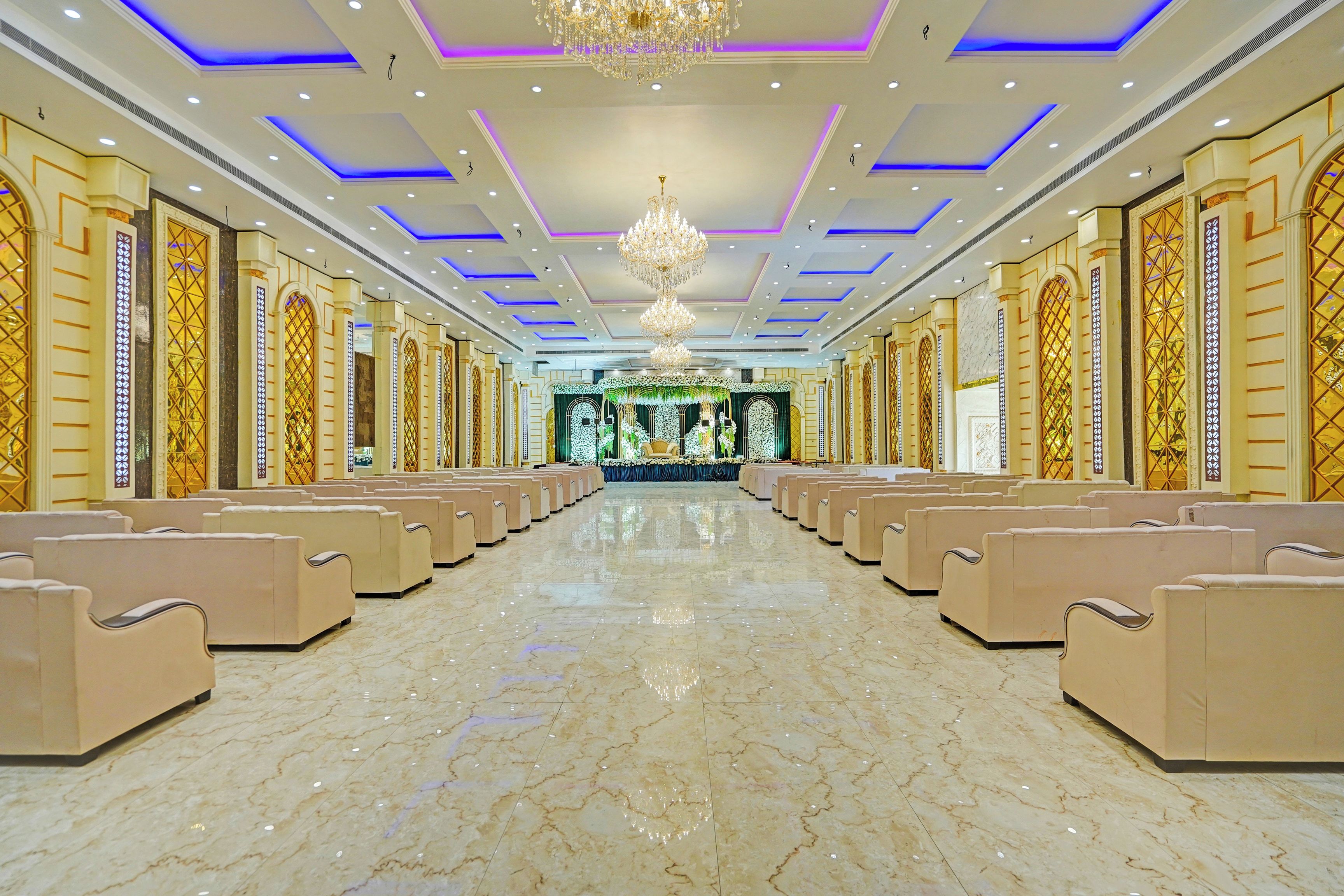 A spacious hall with rows of seating, a chandelier, and ornate wall decorations.