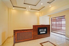 A hotel reception desk with a wooden finish and a sign indicating it is serviced by OYO. - Hotel O JP International Airport Patna (Danapur)