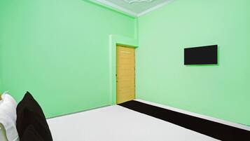 A room with green walls, a white floor, a door, and a black object on the wall.