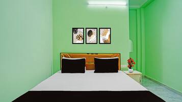 Una habitación con una cama, una mesita de noche con una lámpara y tres cuadros en la pared.