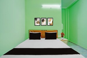 A room with a bed, a nightstand with a lamp, and three framed artworks on the wall. - Hotel O JP International Airport Patna (Danapur)