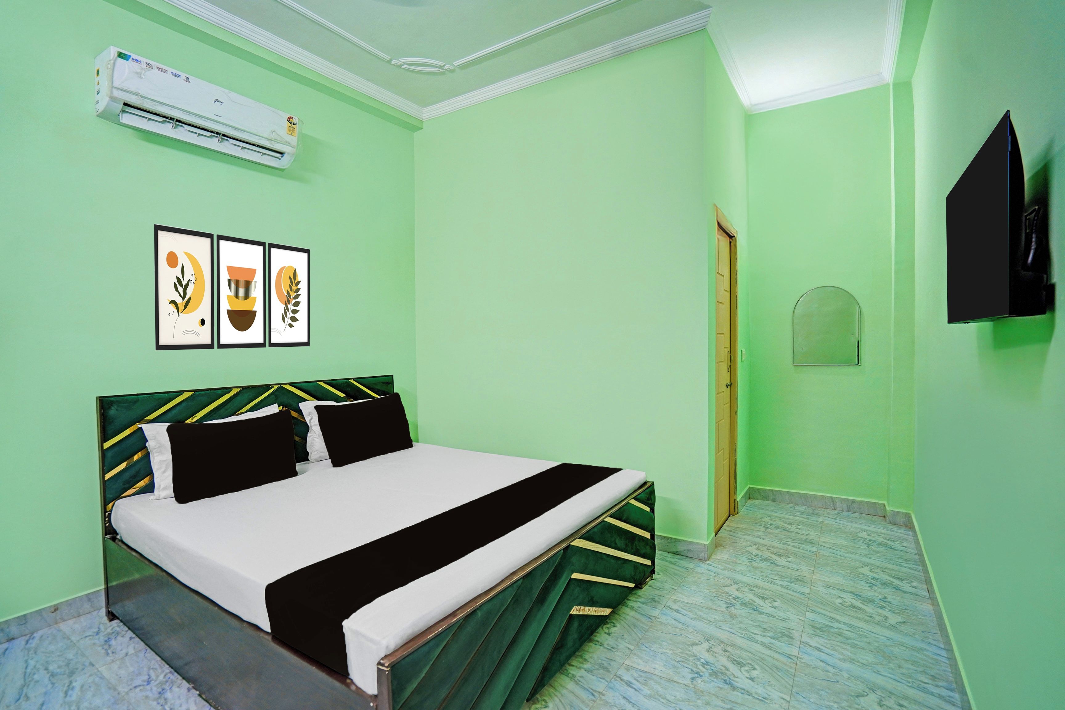 A room with a bed, an air conditioner, and three framed pictures on the wall.