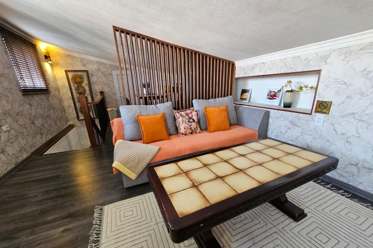 A modern living room with a sofa, a coffee table, and a decorative wall panel.