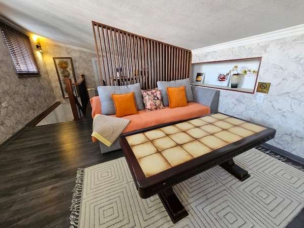 A modern living room with a sofa, a coffee table, and a decorative wall panel.