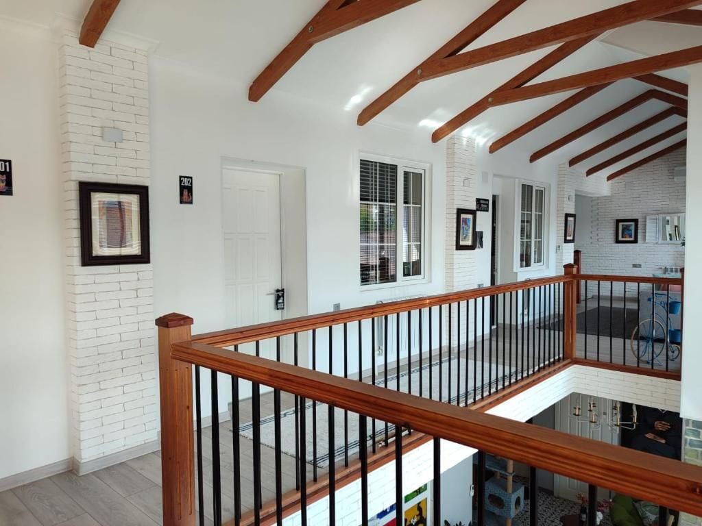Un interior amplio con una escalera de madera, paredes de ladrillo blanco y múltiples ventanas.