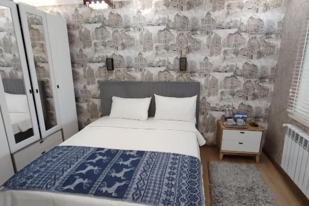 A bedroom with a bed, a wardrobe, a nightstand, and a radiator.