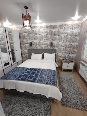 Un dormitorio con cama, armario, mesita de noche y radiador.