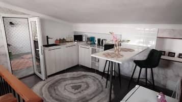 Uma cozinha compacta com área de refeições, geladeira e uma pequena mesa com cadeiras.