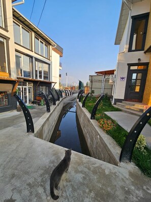 A canal with a bridge, buildings on either side, and a cat on the bridge.