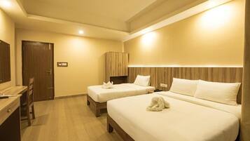 A hotel room with two beds, a desk, and a wardrobe.