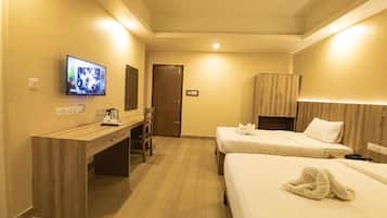Habitación de hotel con escritorio, dos camas, televisor y armario.