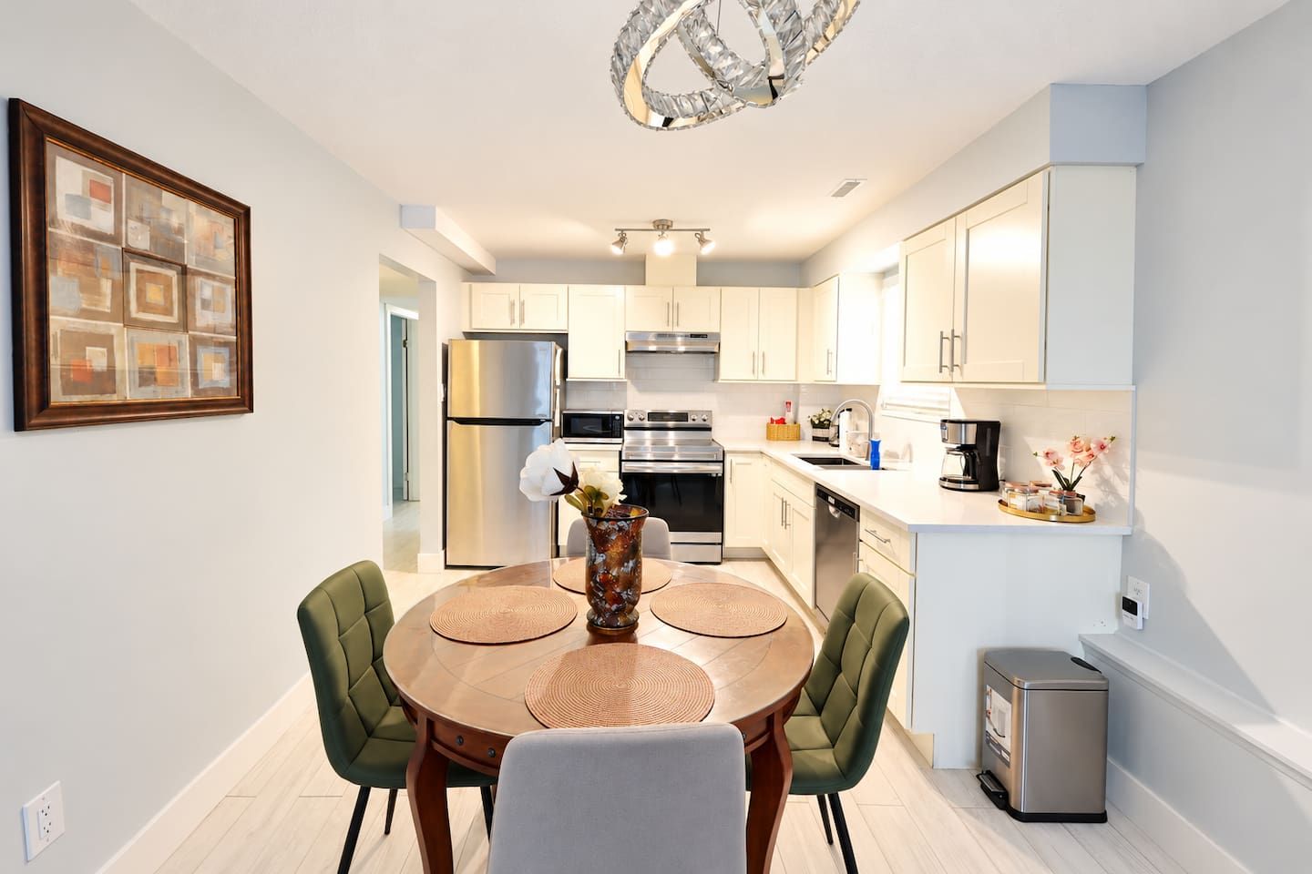 A modern kitchen with a dining area, stainless steel appliances, and a decorative vase on the table.