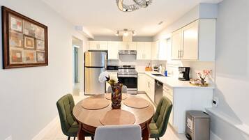 A modern kitchen with a dining area, stainless steel appliances, and a decorative vase on the table.