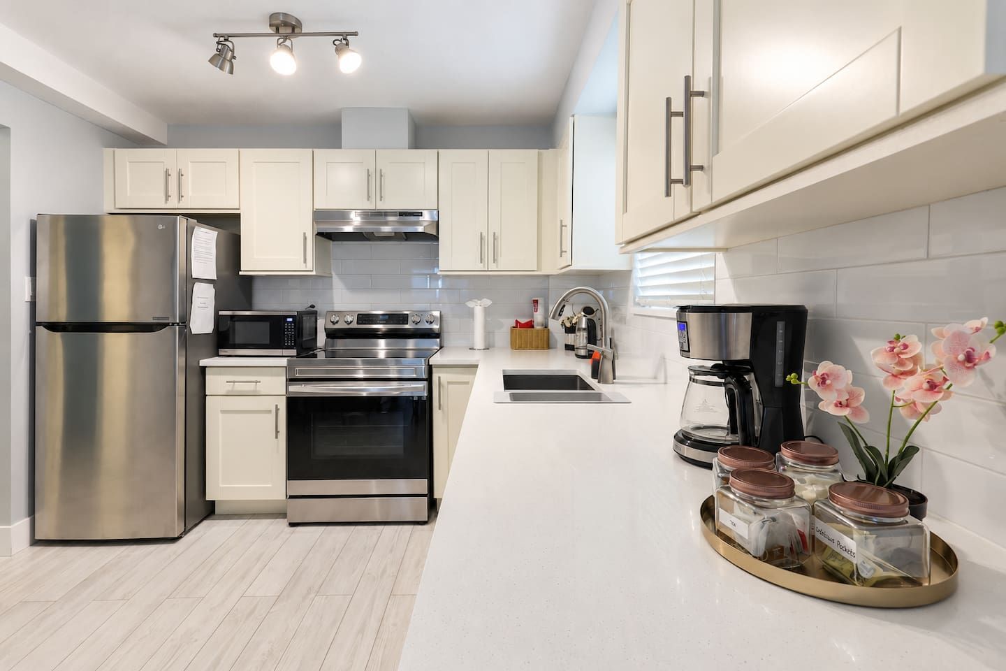 A modern kitchen with stainless steel appliances, white cabinetry, and a coffee maker.