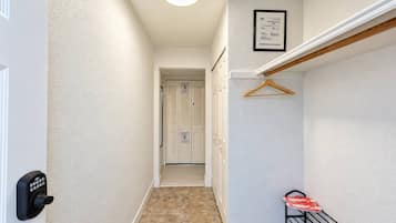 A hallway with a door, a coat rack, and a framed certificate on the wall.