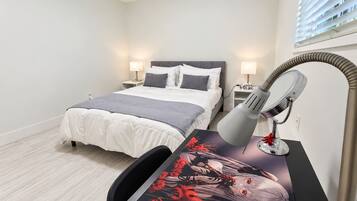 A bedroom with a bed, bedside tables, a desk with a lamp, and a poster.