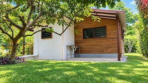 A modern house with a wooden exterior, a small porch, and a well-maintained lawn. - Freshwater Plantation Family Cottage (Canal - Fanafo)