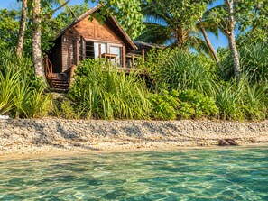 A wooden house with a stone wall and a clear view of the water.
