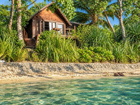 A wooden house with a stone wall and a clear view of the water.