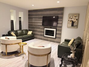 A modern living room with a flat-screen TV, leather sofas, and a fireplace. - Nolan Hill Mountain Gateway | Spacious 4BR Home (Calgary)