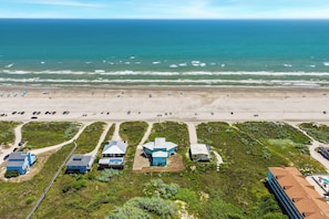A coastal property with multiple buildings, a beach, and a road leading to the ocean. - A Sight for Shore Eyes - Beachfront Home, Sleeps 10 (Please note: The third floor and garage are not available to guests.) (Port Aransas)