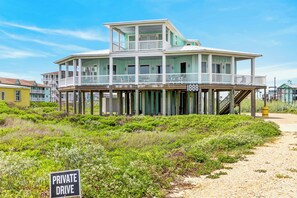 Ein zweistöckiges Strandhaus mit Balkon, einer privaten Einfahrt und direktem Zugang zum Strand.