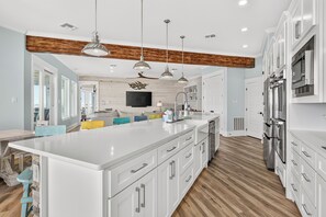 A modern kitchen with white cabinetry, a large island, and stainless steel appliances. - A Sight for Shore Eyes - Beachfront Home, Sleeps 10 (Please note: The third floor and garage are not available to guests.) (Port Aransas)