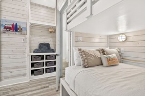 A bedroom with a bunk bed, storage units, and a wall-mounted clock. - A Sight for Shore Eyes - Beachfront Home, Sleeps 10 (Please note: The third floor and garage are not available to guests.) (Port Aransas)