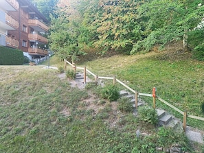 A grassy hillside with a wooden staircase leading up to a building with balconies. - Domino B 38 by Interhome (Ovronnaz)