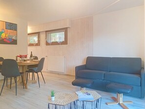 A modern living room with a dark grey sofa, a dining table with chairs, and a small coffee table. - Domino B 38 by Interhome (Ovronnaz)