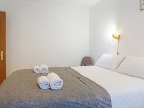 A hotel room with a bed, a grey blanket, and rolled towels on the bed. - Domino B 38 by Interhome (Ovronnaz)