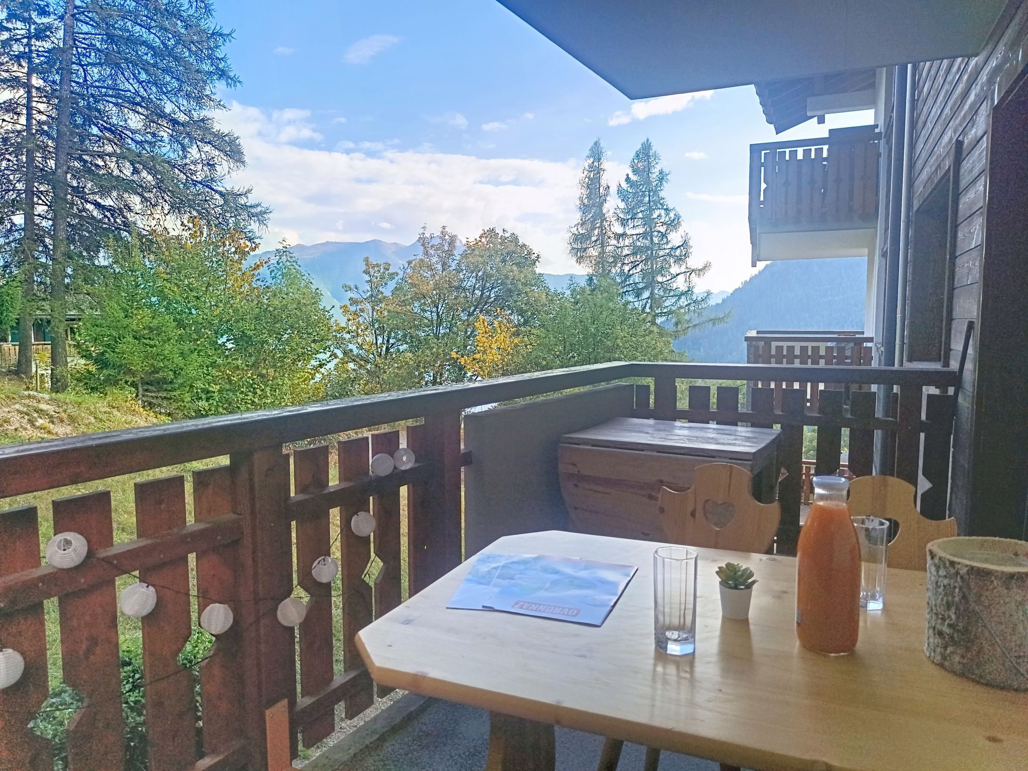 Une terrasse en bois avec une table, des chaises et une vue sur les montagnes.