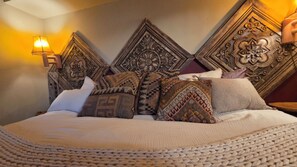 A bed with a knitted throw, multiple pillows with patterns, and a wall with ornate wood paneling. - Pine Beach Peninsula iconic property on Gull Lake. Truly one of a kind & special (City of East Gull Lake)