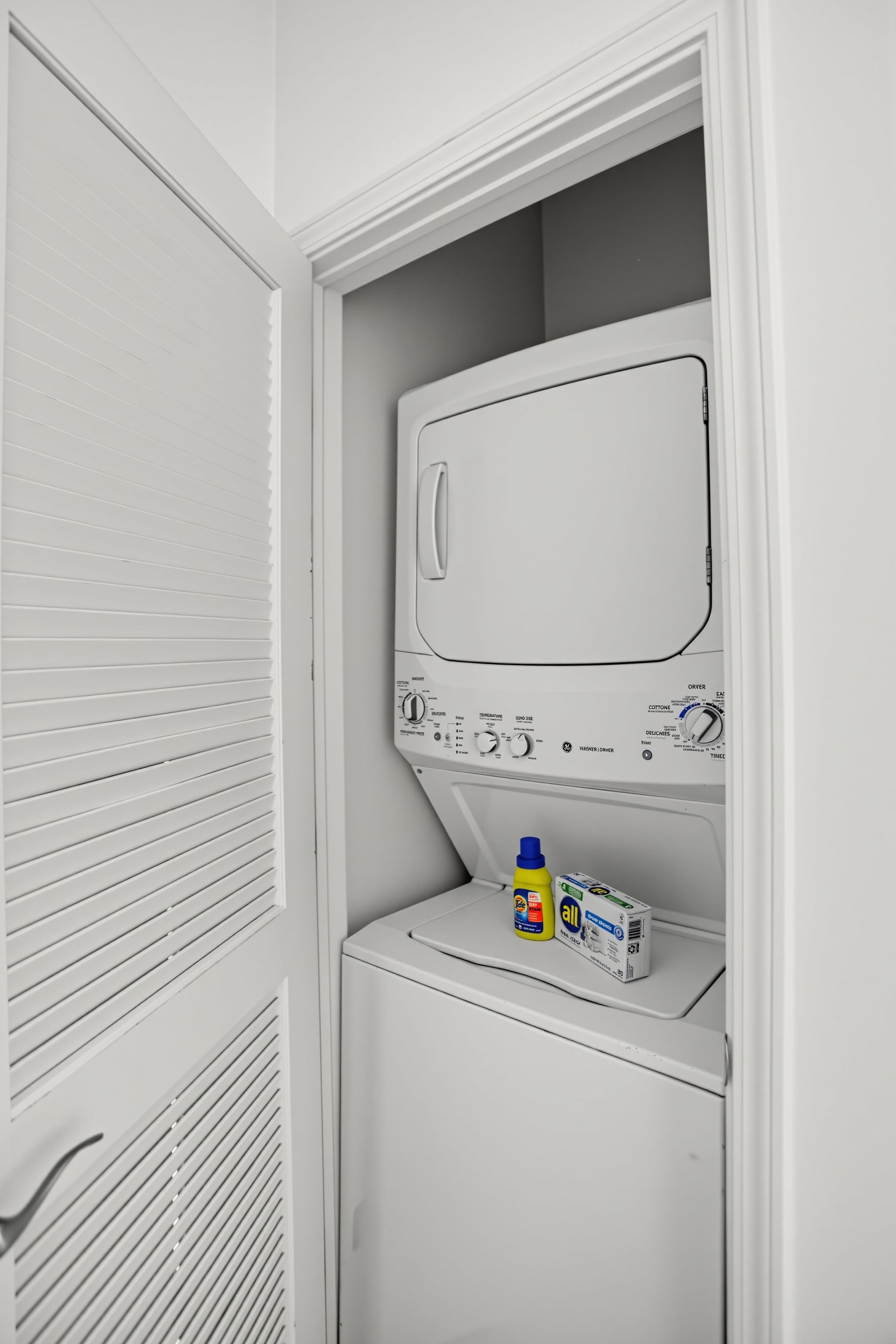 Een kleine, witte wasruimte met een voorlader wasmachine en een droger.