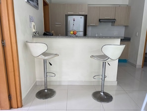 A modern kitchen with two bar stools, a refrigerator, and a sink. - Modern apartment in Gazcue, near the Zona Colonial - Malecón (Santo Domingo)