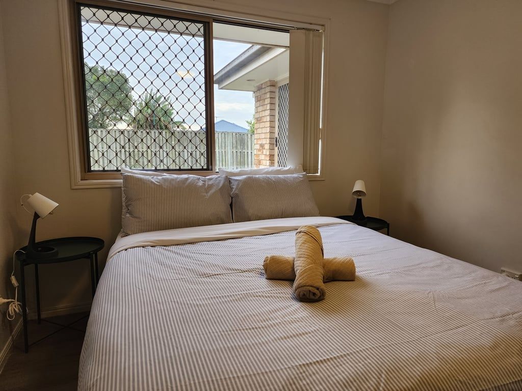 A hotel room with a bed, two bedside tables, a window with a view, and a towel on the bed.