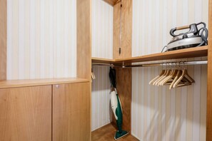 A wooden closet with a hanging rack and a vacuum cleaner. - Villa Sinfonia, Exclusive Villa in Ravello (Ravello)