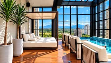 Una habitación moderna con un ventanal grande, un sofá, una piscina y plantas en macetas.