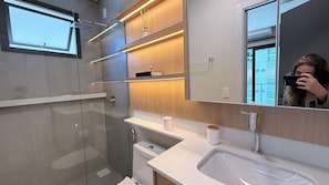 Ein modernes Badezimmer mit Duschkabine aus Glas, einem weißen Waschbecken und einem Spiegel, der Stadtansichten zeigt.