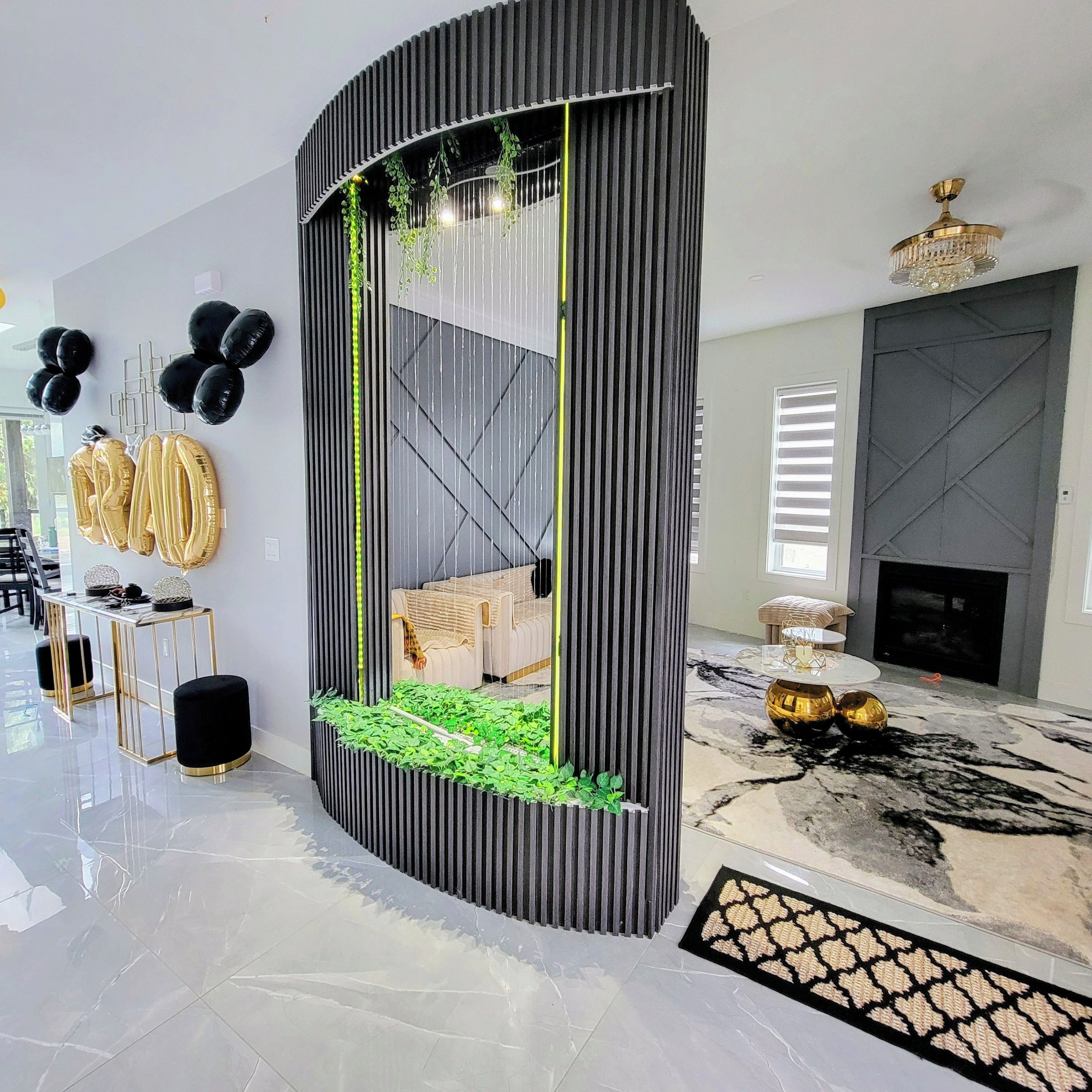 Un salon moderne doté d’une cloison noire aux lignes courbes, d’un canapé, d’une cheminée et d’un sol en marbre.