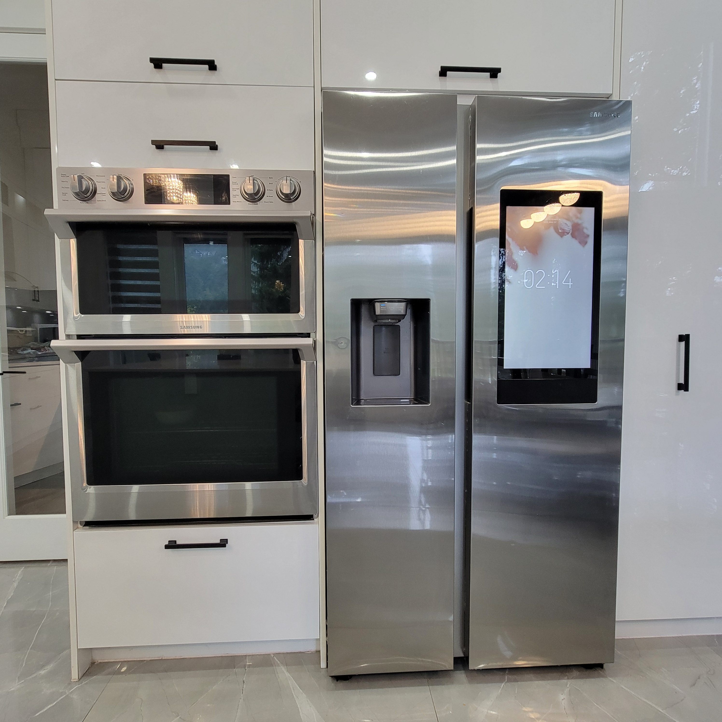A stainless steel kitchen with a built-in oven and a refrigerator with a digital display.