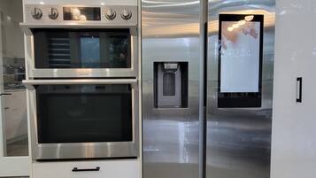 A stainless steel kitchen with a built-in oven and a refrigerator with a digital display.