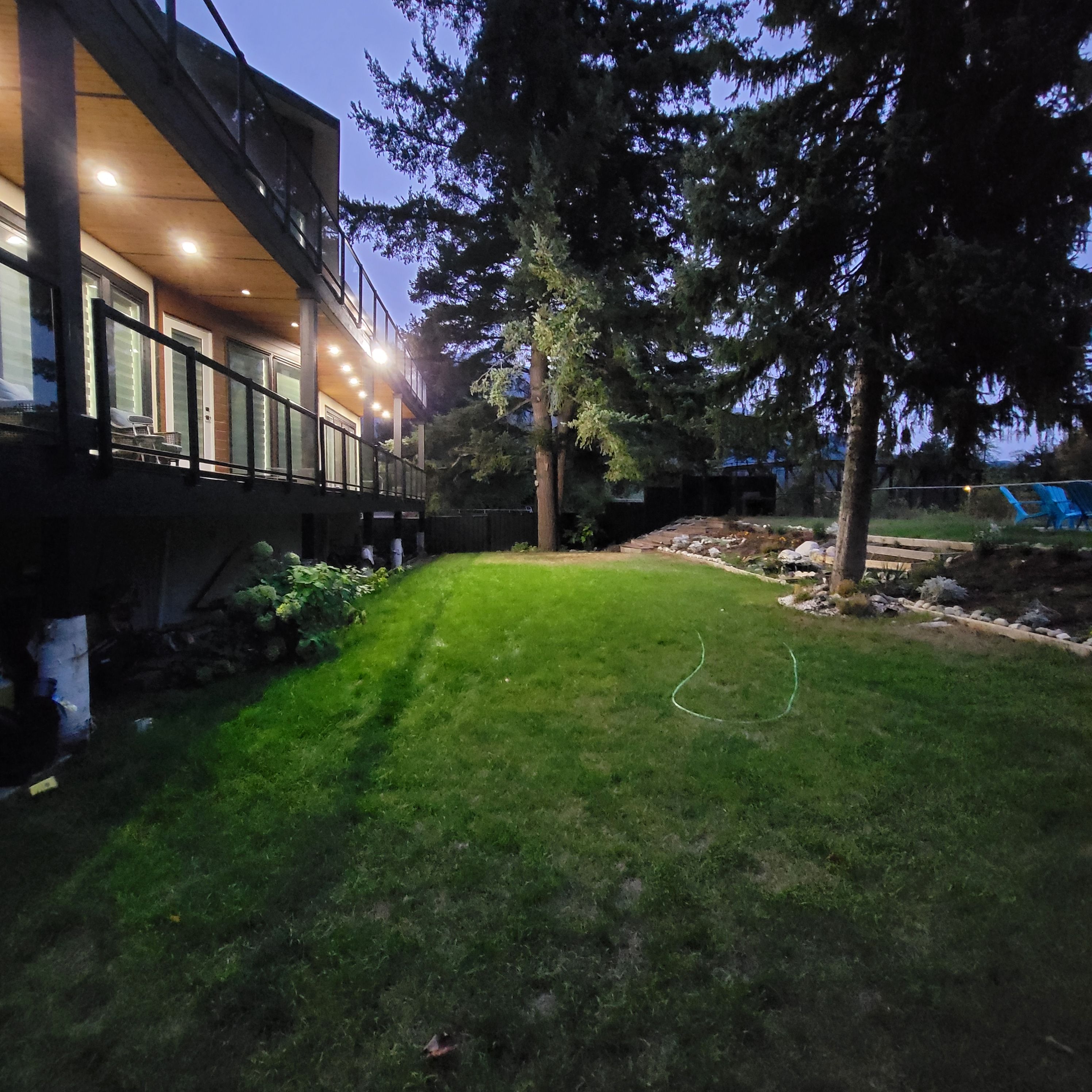 A residential property with a well-maintained lawn, a wooden deck, and a large tree.