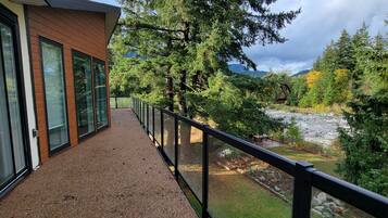 A balcony with a gravel floor, overlooking a garden with trees and a river.