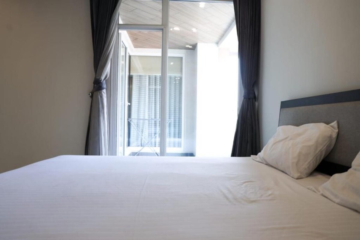 Habitación de hotel con una cama grande, cabecera y vistas a un balcón a través de una puerta de cristal.