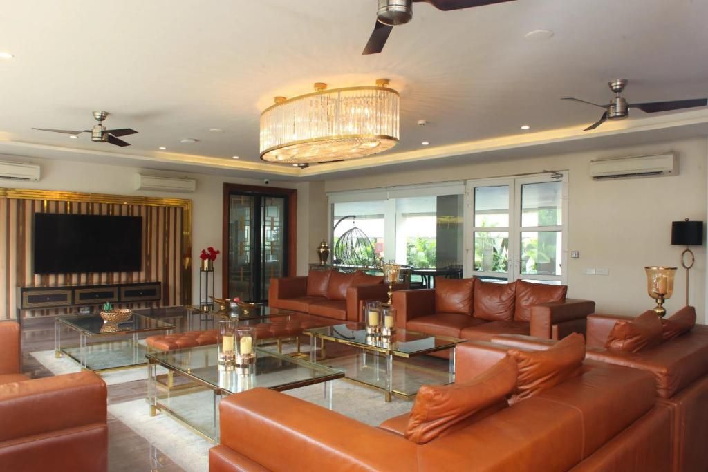 A spacious living room with leather sofas, glass coffee tables, and a large flat-screen TV.