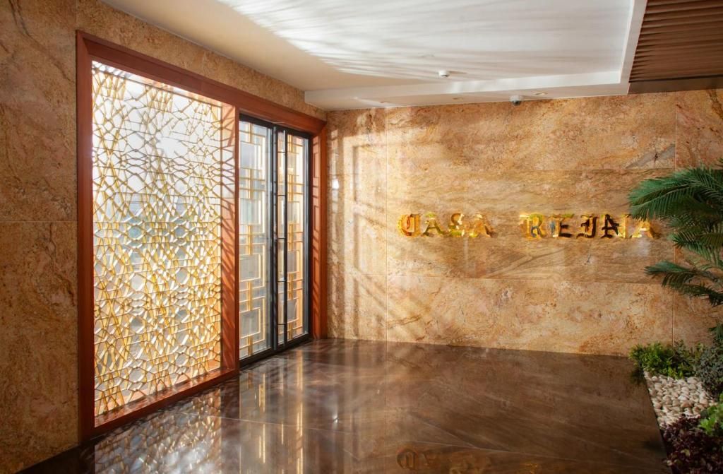 A lobby with a marble wall and a decorative glass partition.