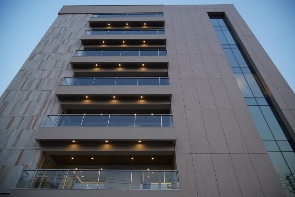 Un immeuble à plusieurs étages doté d’une architecture moderne, caractérisé par une série de balcons et de grandes fenêtres.
